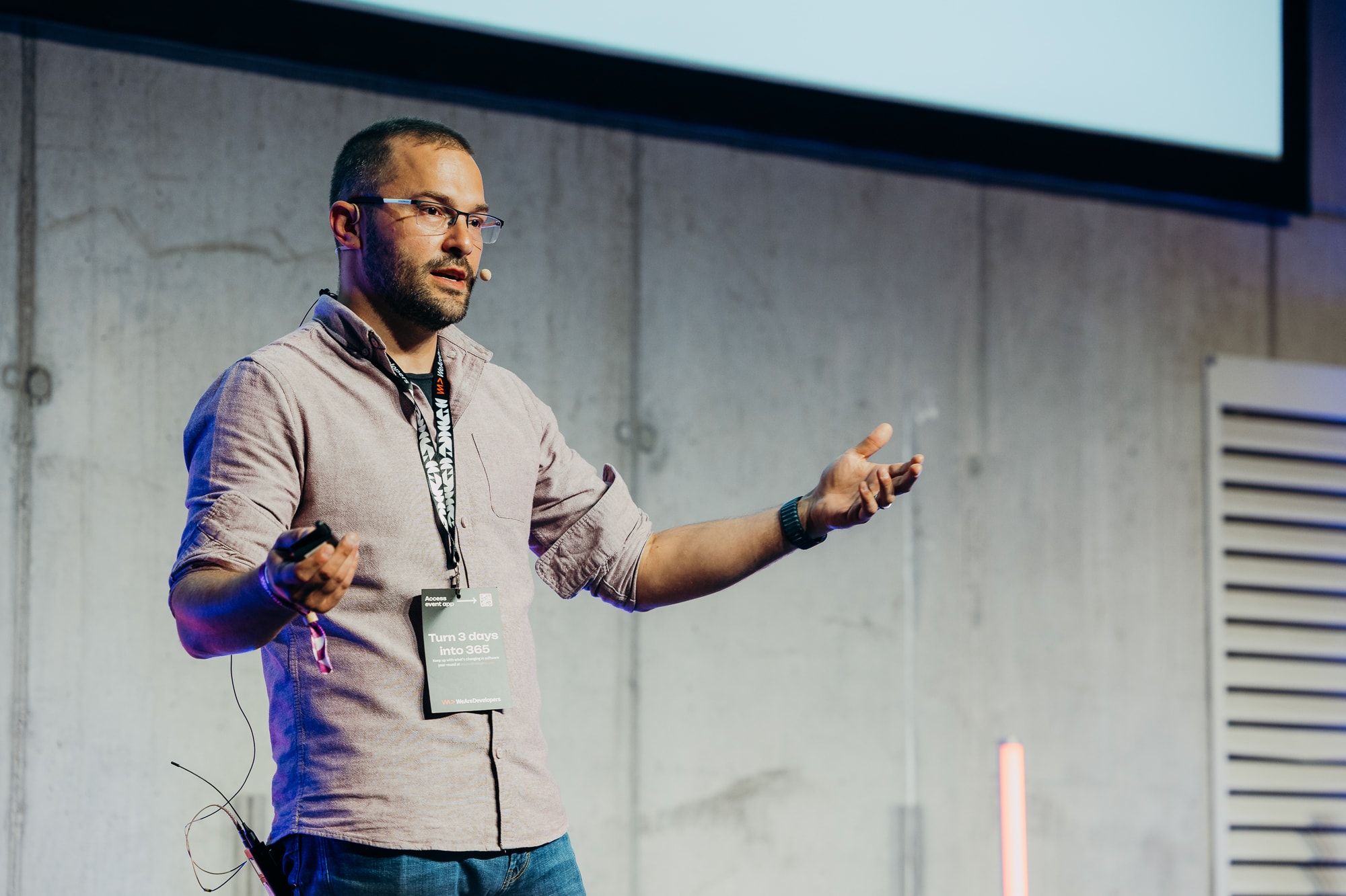 Sasa Fajkovic mid-sentence with a headset microphone, gesturing with an open hand, at WeAreDevelopers World Congress 2026